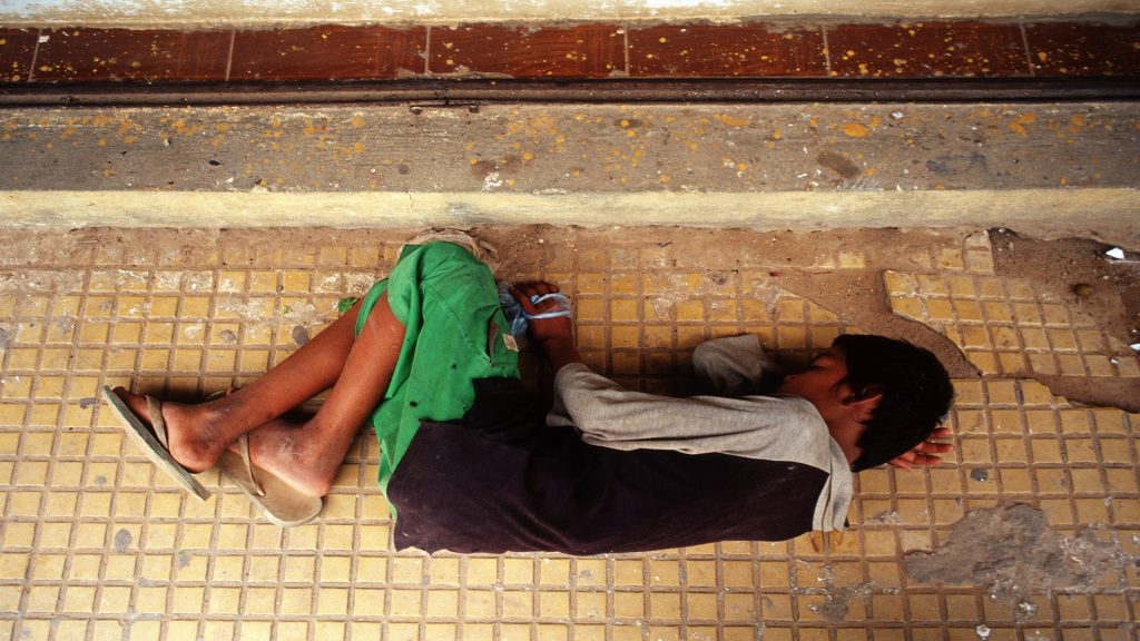 With his bag of glue wrapped tightly in his hand, a teenage